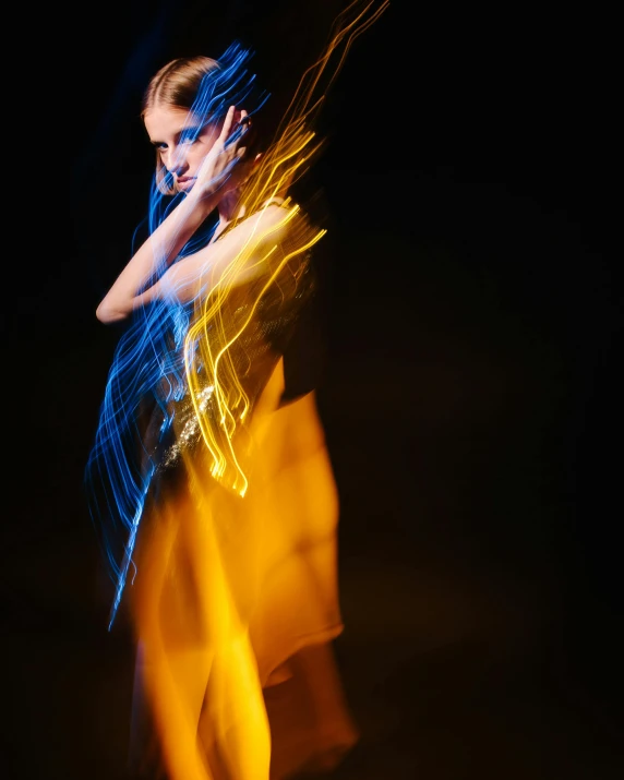 a woman that is standing in the dark, by Jan Rustem, art photography, neon blue and yellow lights, orange spike aura in motion, translucent dress, shot on sony a 7