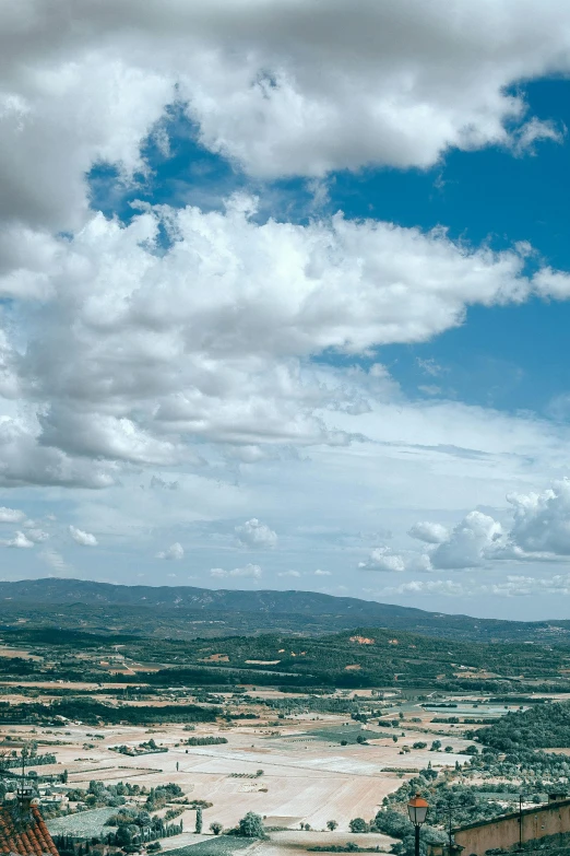 a man riding a motorcycle down a dirt road, inspired by Jan Rustem, unsplash contest winner, renaissance, panorama view of the sky, lourmarin, large white clouds, entire city in view