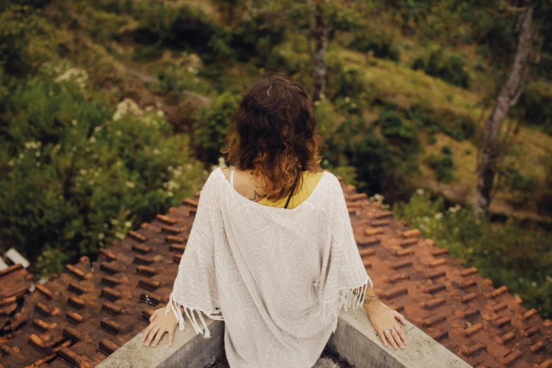 a woman sitting on top of a roof, trending on pexels, cottagecore hippie, view from back, wearing a blouse, health spa and meditation center