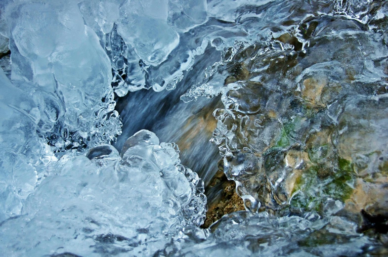 a close up of a stream of water with ice on it, by Mandy Jurgens, pexels contest winner, whirlpool, cold colours, ignant, mountain water