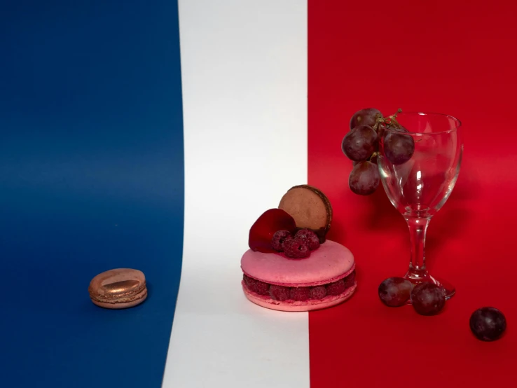 a dessert sitting on top of a table next to a glass of wine, a still life, inspired by François Louis Thomas Francia, pexels contest winner, french flag, mauve and cinnabar and cyan, portrait 4 / 3, urban surroundings