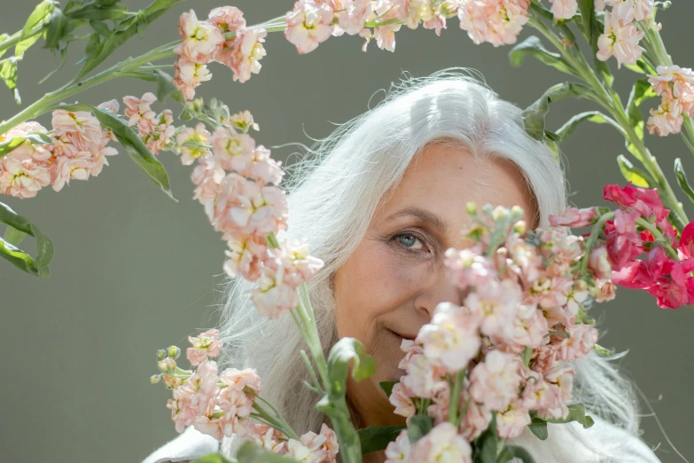 a woman holding a bouquet of flowers in front of her face, inspired by Grethe Jürgens, pexels contest winner, light gray long hair, sakura season, profile image, the look of an elderly person