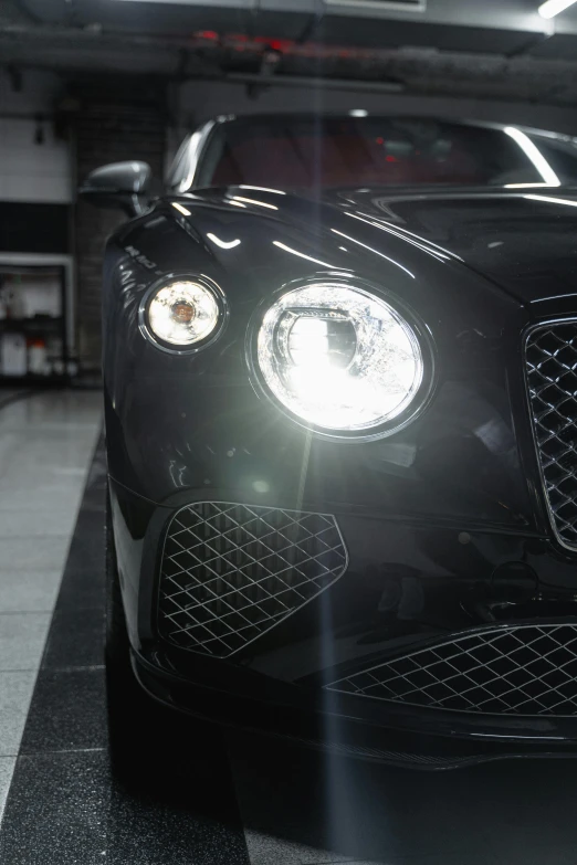 a black car is parked in a garage, headlights are on, bentley, superdetail, cinematics lighting