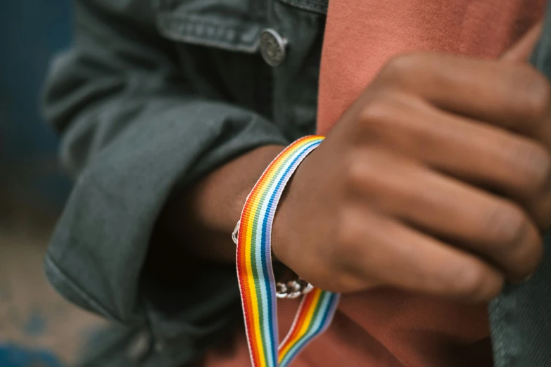 a close up of a person wearing a bracelet, trending on pexels, lgbt, ribbon, patron saint of 🛸🌈👩🏾, exterior shot