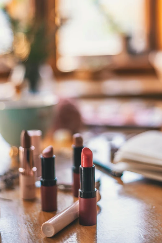 a group of lipstick sitting on top of a wooden table, renaissance, putting makeup on, curated collections, blurred, skincare