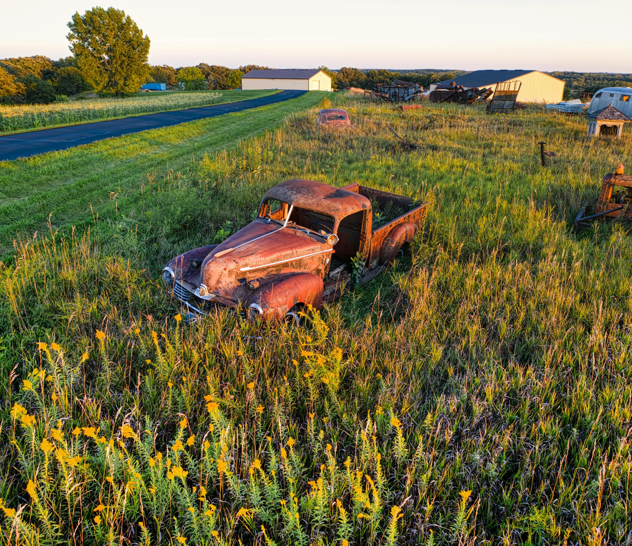 an old truck sitting in the middle of a field, by Arnie Swekel, unsplash, auto-destructive art, late summer evening, minn, overgrown city, wide high angle view