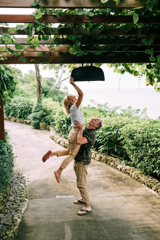 a man carrying a woman up in the air, unsplash, happening, lush gardens hanging, jamaica, kate oleska and jim kay, at home