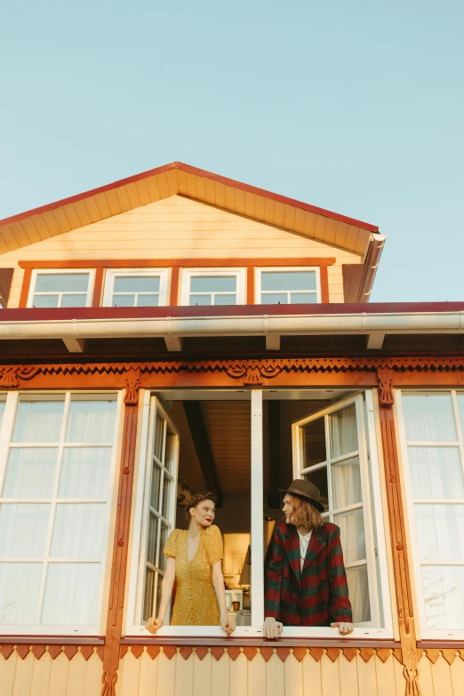 a man and a woman looking out of a window, unsplash, luxurious wooden cottage, red - yellow - blue building, golden hour in pismo california, slide show