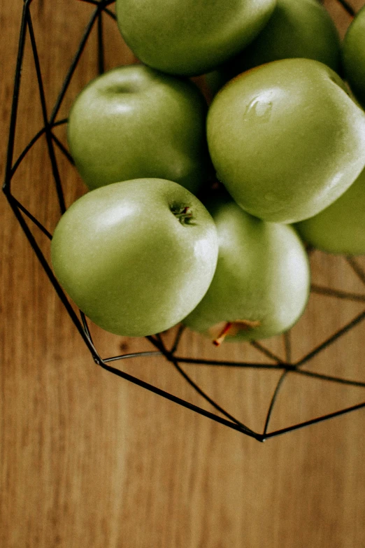 a bowl filled with green apples on top of a wooden table, geometric but organic, organic steel, sleek design, grid