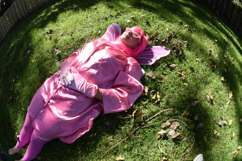 a woman laying on top of a lush green field, an album cover, inspired by Modest Urgell, flickr, hurufiyya, pink clothes, halloween, moroccan queens ny, taken in the late 2010s