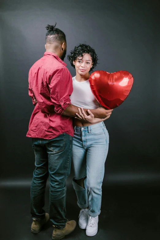 a man standing next to a woman holding a heart shaped balloon, by Cosmo Alexander, pexels, renaissance, dark grey backdrop studio, african american, casual pose, gif