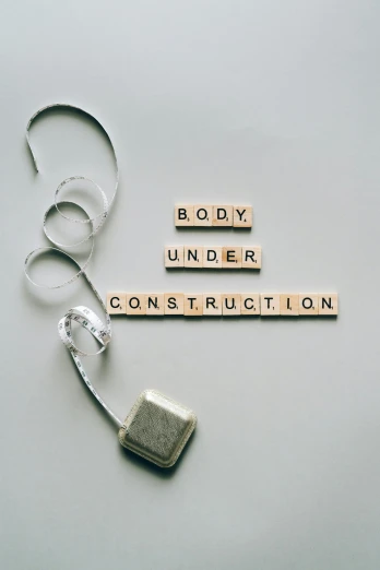 a cell phone with the words body under construction spelled in scrabbles, an album cover, pexels contest winner, constructivism, skincare, gray concrete, perfect body shape, wiring