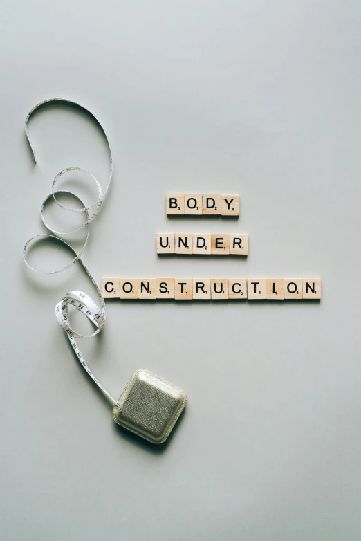 a cell phone with the words body under construction spelled in scrabbles, an album cover, pexels contest winner, constructivism, skincare, gray concrete, perfect body shape, wiring