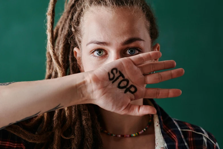 a woman with dreadlocks covering her face with her hands, trending on pexels, antipodeans, stop sign, avatar image, aloy, 18 years old