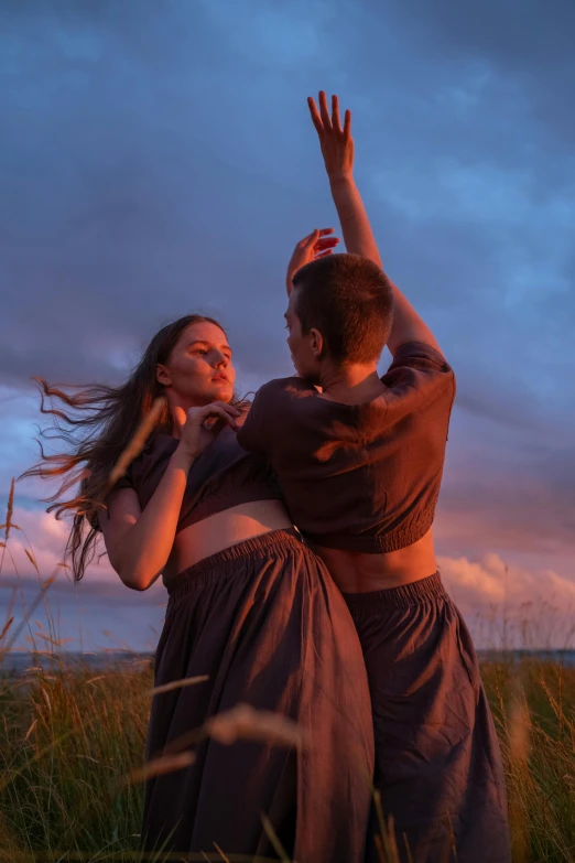 a couple of people that are standing in the grass, a portrait, by Else Alfelt, unsplash, renaissance, contemporary dance, dusk, coastal, lesbians