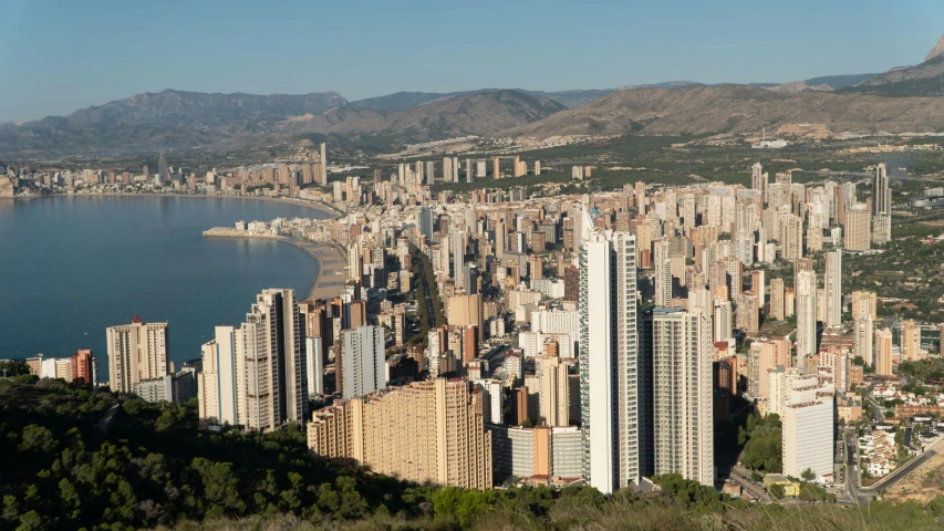 a view of a city from the top of a hill, by Lee Loughridge, unsplash, costa blanca, aerial photograph of skyscraper, brown, tropical coastal city