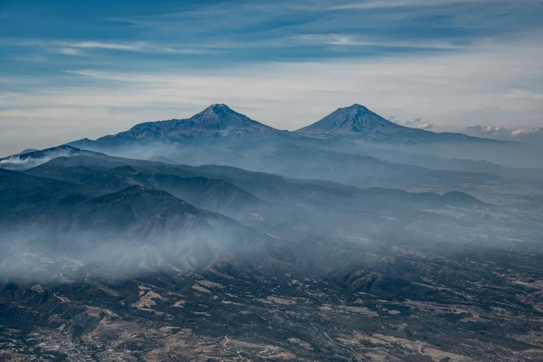 a view of the mountains from an airplane, a photo, pexels contest winner, visual art, infographic of active volcanoes, mexican standoff, dezeen, two mountains in background