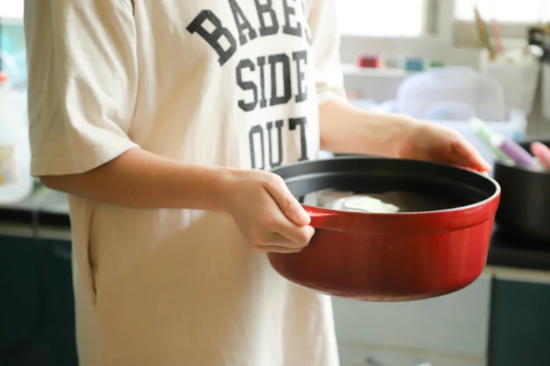 a person holding a pan of food in a kitchen, a picture, red shirt, for kids, metal lid, iwakura