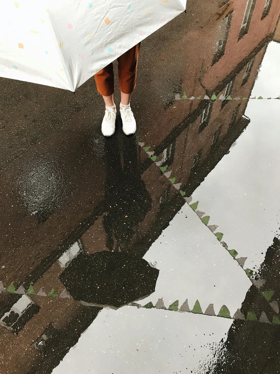 a woman standing in the rain holding an umbrella, a picture, by Anna Haifisch, wearing white sneakers, iphone photo, reflects, 8 k photo