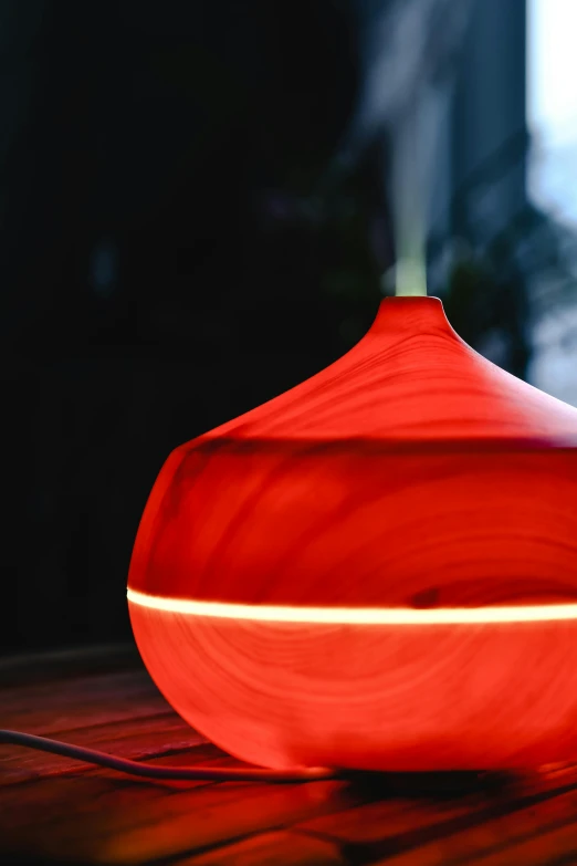 a red vase sitting on top of a wooden table, glowing swirling mist, product design shot, tear drop, cosy