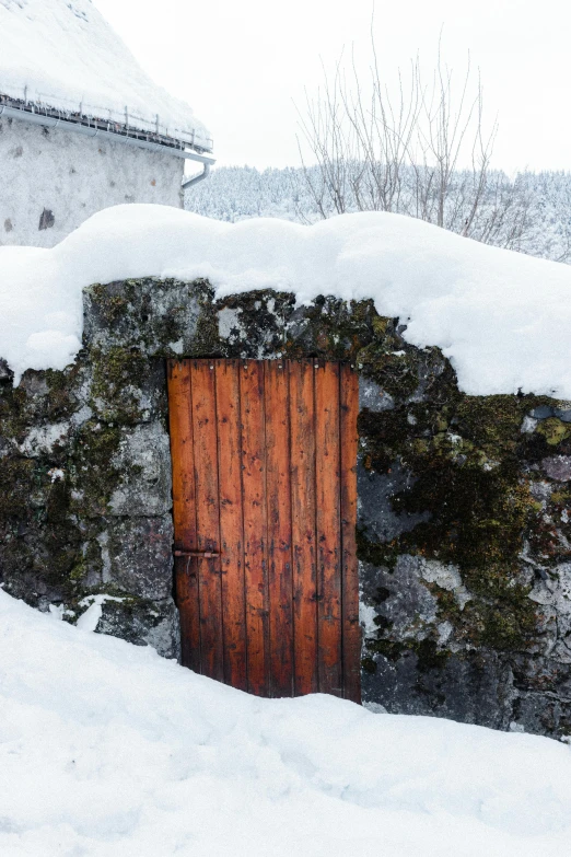 an old stone building with a wooden door in the snow, inspired by Einar Hakonarson, les nabis, natural cave wall, torri gate, intense colours, exterior