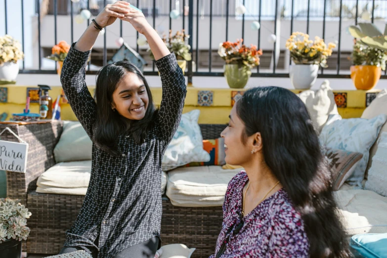 a couple of women sitting on top of a couch, pexels contest winner, hurufiyya, greeting hand on head, indian girl with brown skin, families playing, looking upward