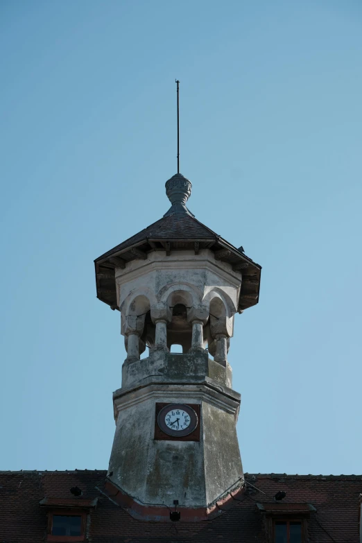 a clock tower on top of a building, stone roof, taken in the early 2020s, clear sky above, square