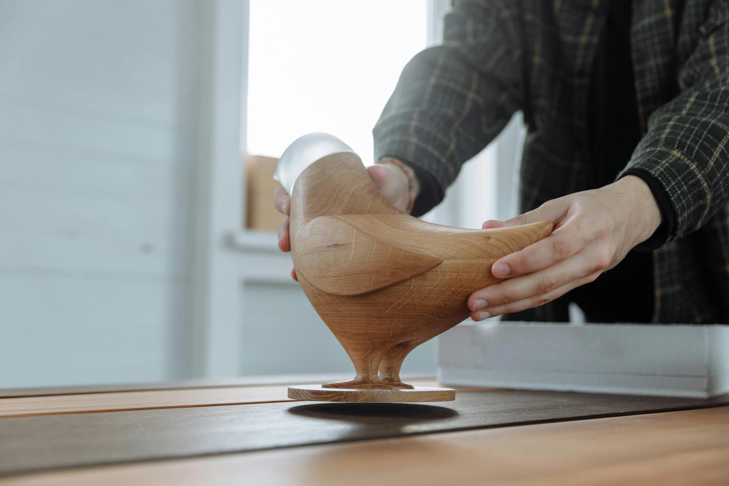 a person holding a wooden object on a table, inspired by Isamu Noguchi, unsplash contest winner, kinetic art, duck shaped spaceship, pouring, hyper realistic detailed render, clear curvy details