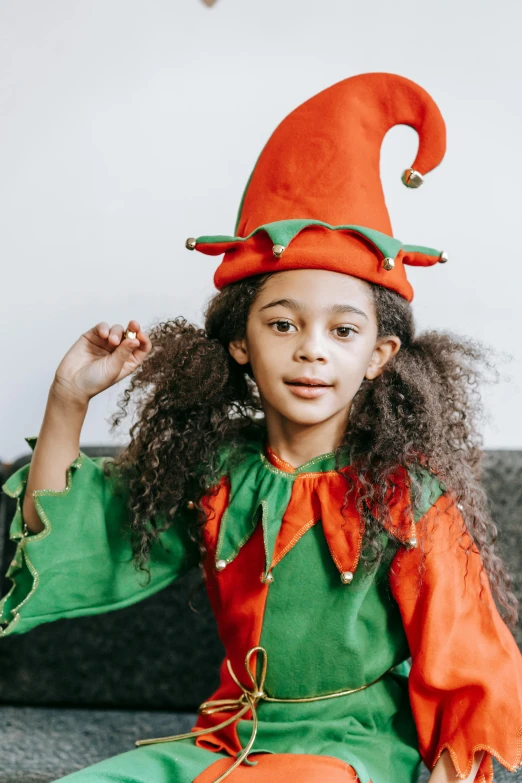 a little girl in an elf costume sitting on a couch, pexels contest winner, renaissance, varying ethnicities, pointy hat, thumbnail, african american girl