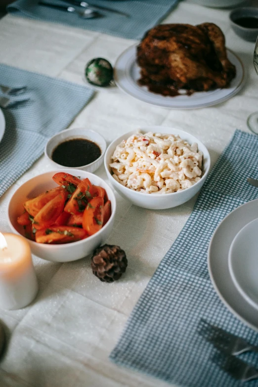 a table topped with bowls of food next to a candle, renaissance, white and orange, rice, holiday season, profile image