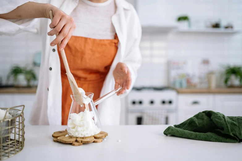 a woman in an orange apron is making marshmallows, by Julia Pishtar, trending on pexels, best mayonnaise, inside a glass jar, manuka, white