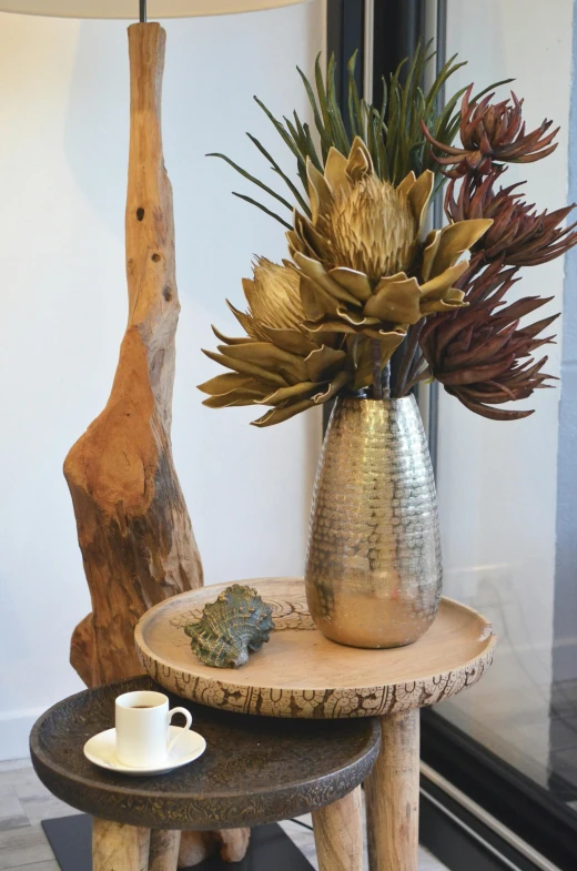 a vase sitting on top of a wooden table next to a lamp, shades of gold display naturally, bromeliads, close up details, breakfast