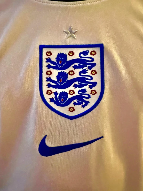 a t - shirt with the england crest on it, by Tom Wänerstrand, trending on dribble, symbolism, 2 0 0 0's photo, nike logo, closeup - view, embroidery