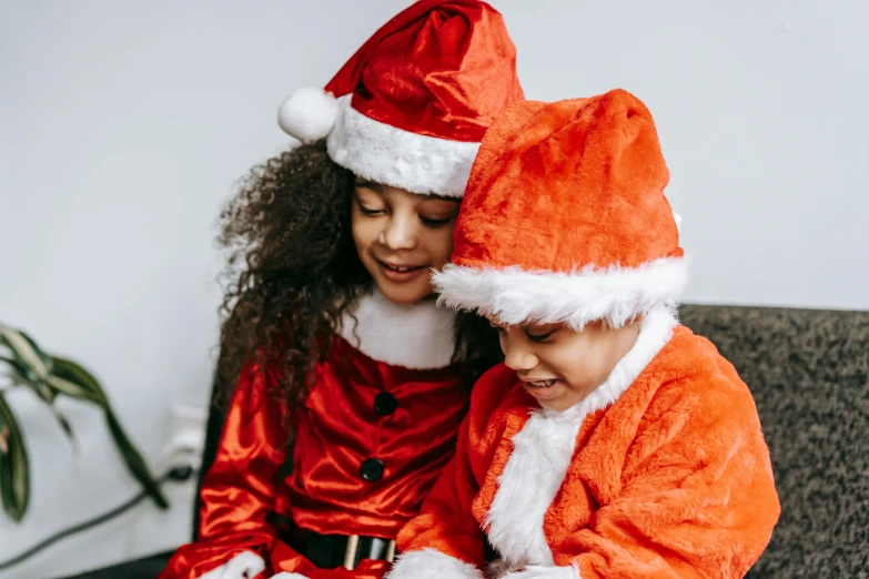 a couple of kids sitting on top of a couch, pexels, santa clause, profile image, wearing red attire, diverse