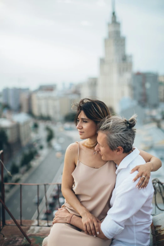 a man and a woman sitting on top of a building, trending on unsplash, romanticism, gray haired, russian girlfriend, wide open city ”, arm around her neck