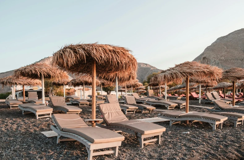 a bunch of lounge chairs and umbrellas on a beach, by Julia Pishtar, pexels contest winner, black volcano afar, olive trees, boutinela bikini, at the terrace