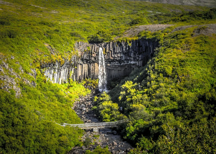 a waterfall in the middle of a lush green valley, by Hallsteinn Sigurðsson, pexels contest winner, hurufiyya, old lumber mill remains, thumbnail, rocky cliff, dessert