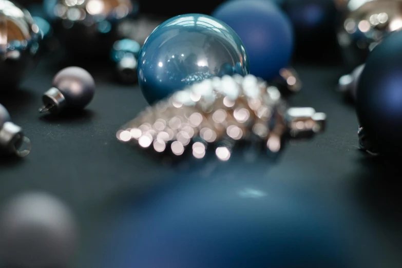 a bunch of blue and silver ornaments on a table, inspired by Perle Fine, trending on unsplash, photorealism, cinematic shot ar 9:16 -n 6 -g, medium close up shot, spheres, angled shot