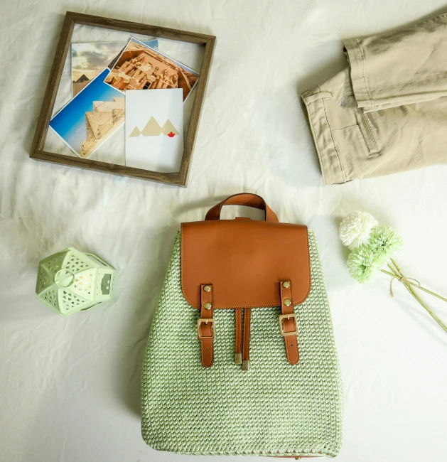 a backpack sitting on top of a bed next to a picture frame, inspired by Art Green, instagram, green and brown clothes, flat lay, summer feeling, crochet