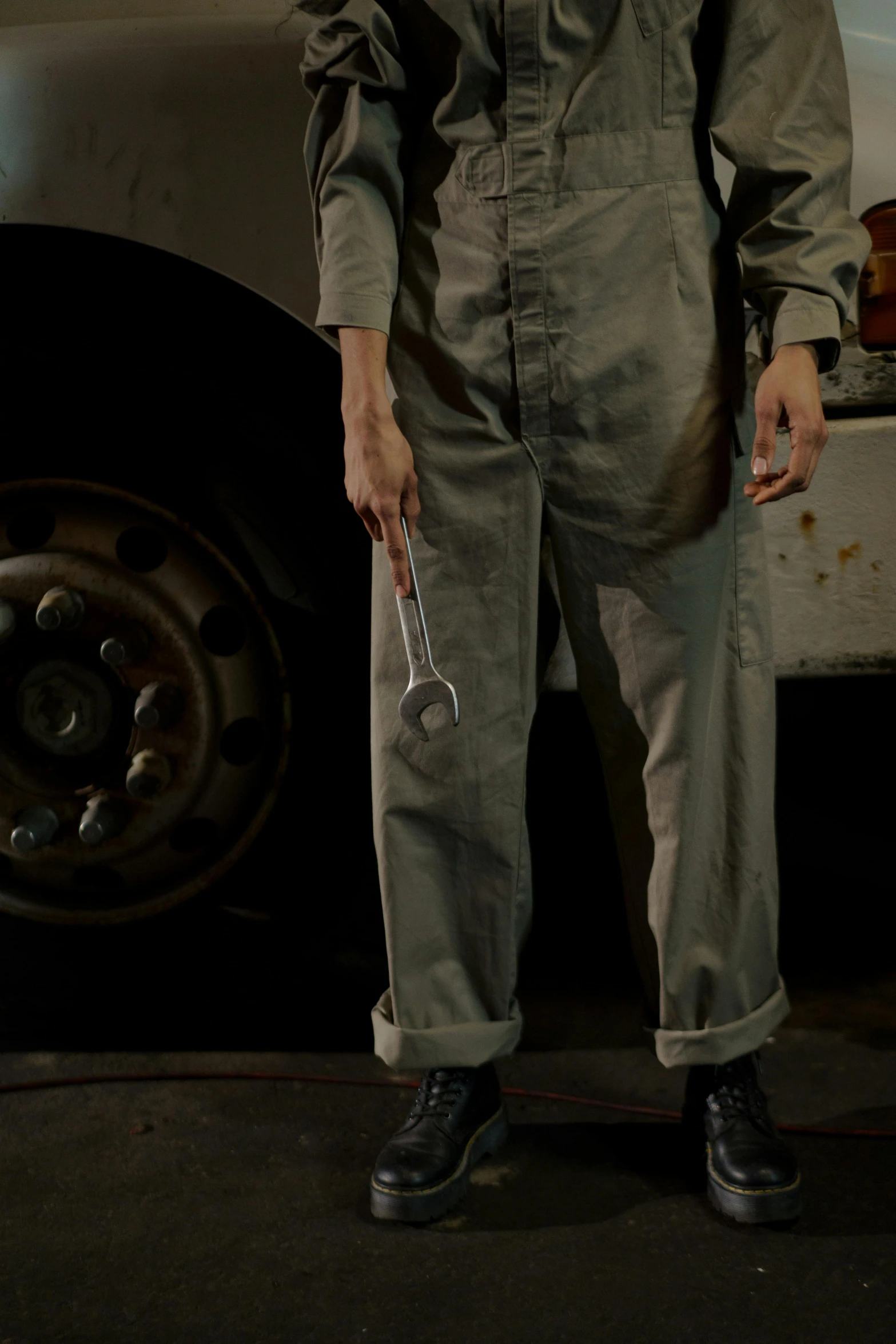 a man standing in front of a white truck, a colorized photo, by Ben Zoeller, pexels contest winner, photorealism, holding a wrench, wearing human air force jumpsuit, khakis, on a dark background