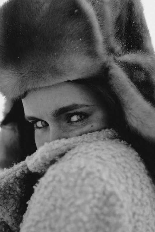 a black and white photo of a woman wearing a fur hat, inspired by Sergio Larraín, ice-blue-eyes, brooke shields, square, close-up!!!!!