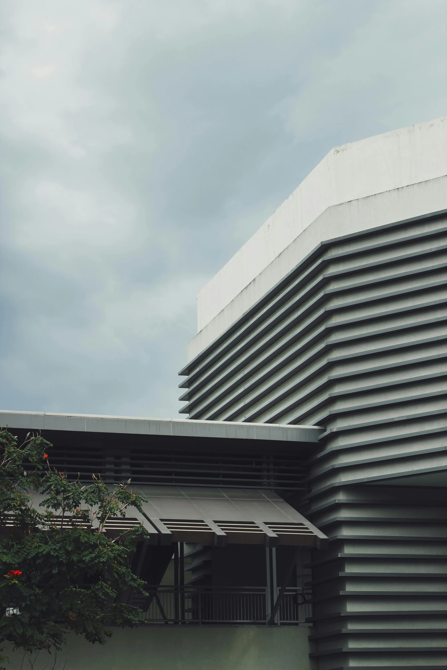 a tall building sitting on top of a lush green field, inspired by David Chipperfield, unsplash, brutalism, malaysian, concert hall, close - up profile, street corner