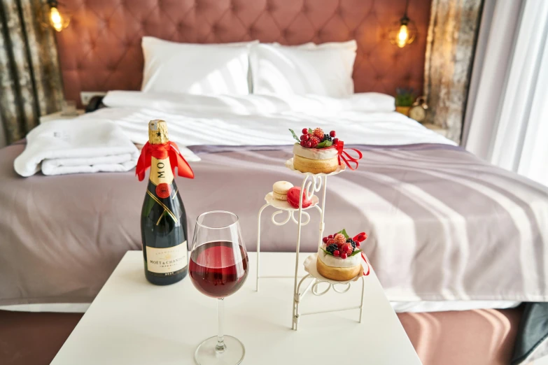 a bed room with a neatly made bed and a glass of wine, romanticism, desserts, ekaterina, premium quality, bubbly