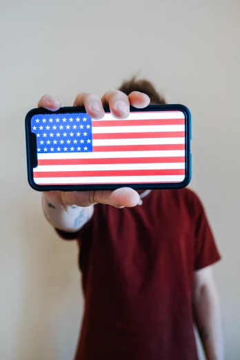 a person holding up a cell phone with an american flag on it, profile image