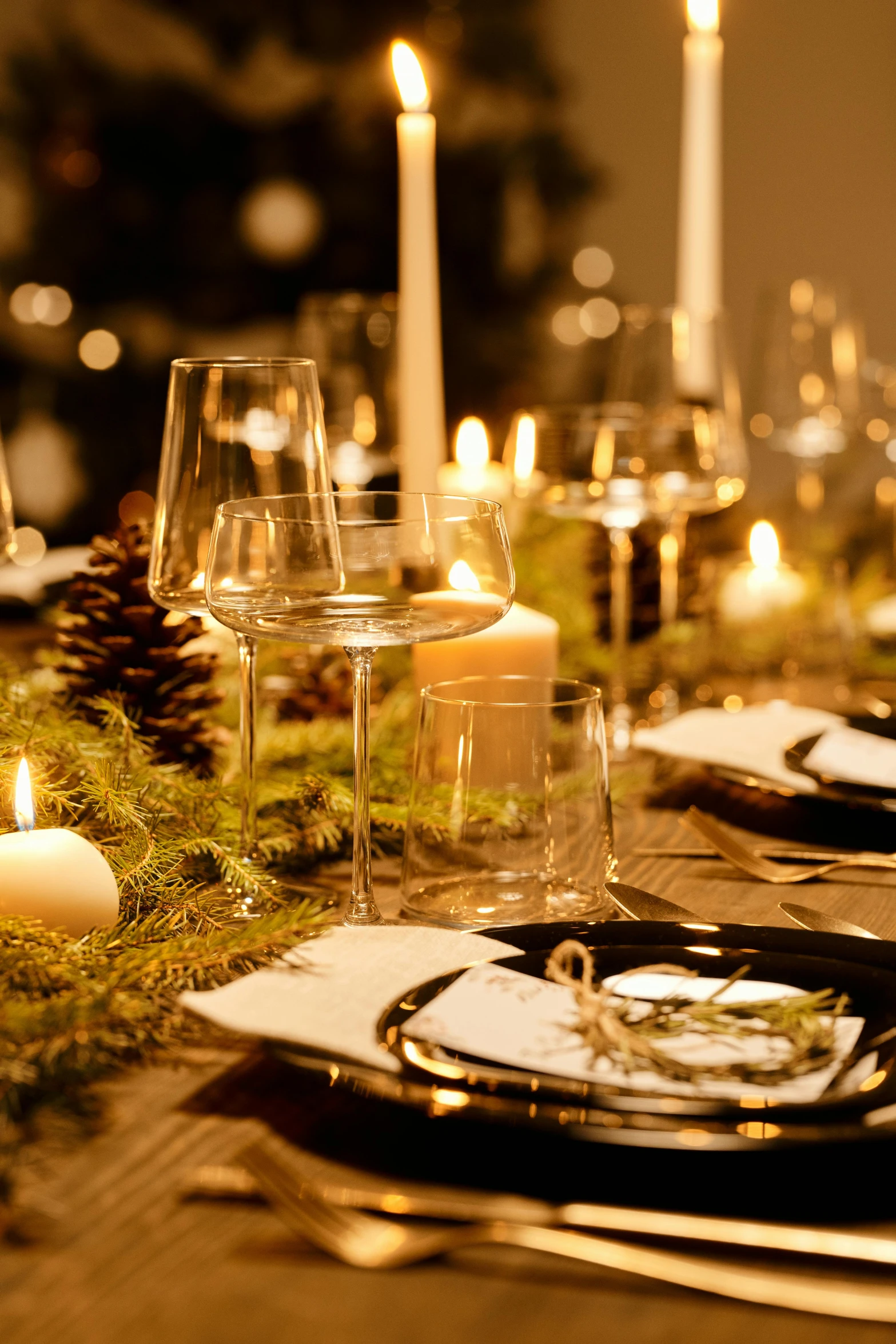 a table is set with candles and place settings, renaissance, evergreen branches, warm ambient lighting, modern, sparkling spirits