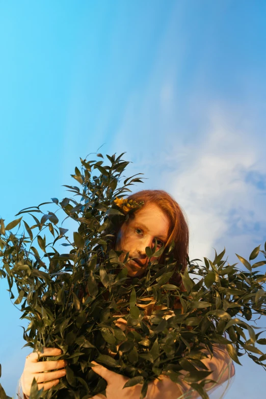 a woman holding a bush in front of her face, an album cover, inspired by Ren Hang, unsplash, fantastic realism, redhead woman, blue skies, late evening, portrait shot 8 k