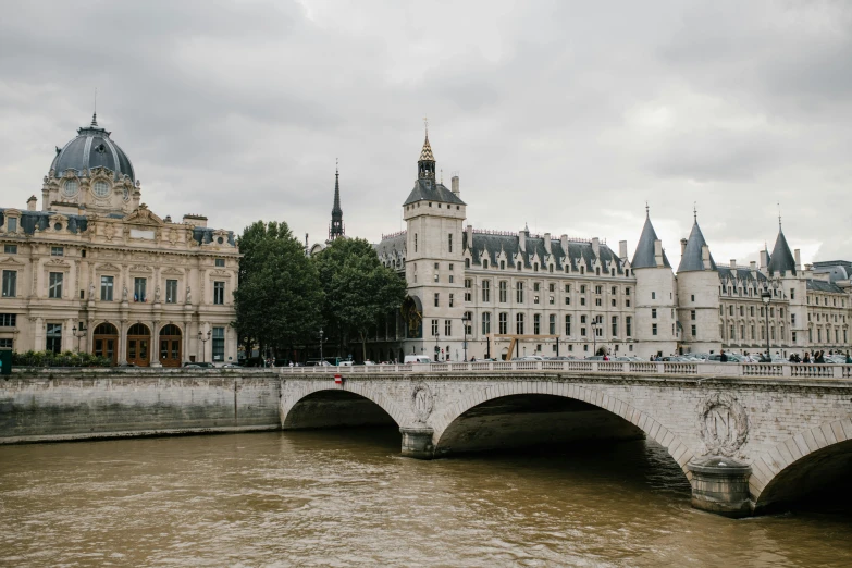 a bridge over a river with buildings in the background, a photo, pexels contest winner, paris school, white sweeping arches, royal photo, a cozy, white building