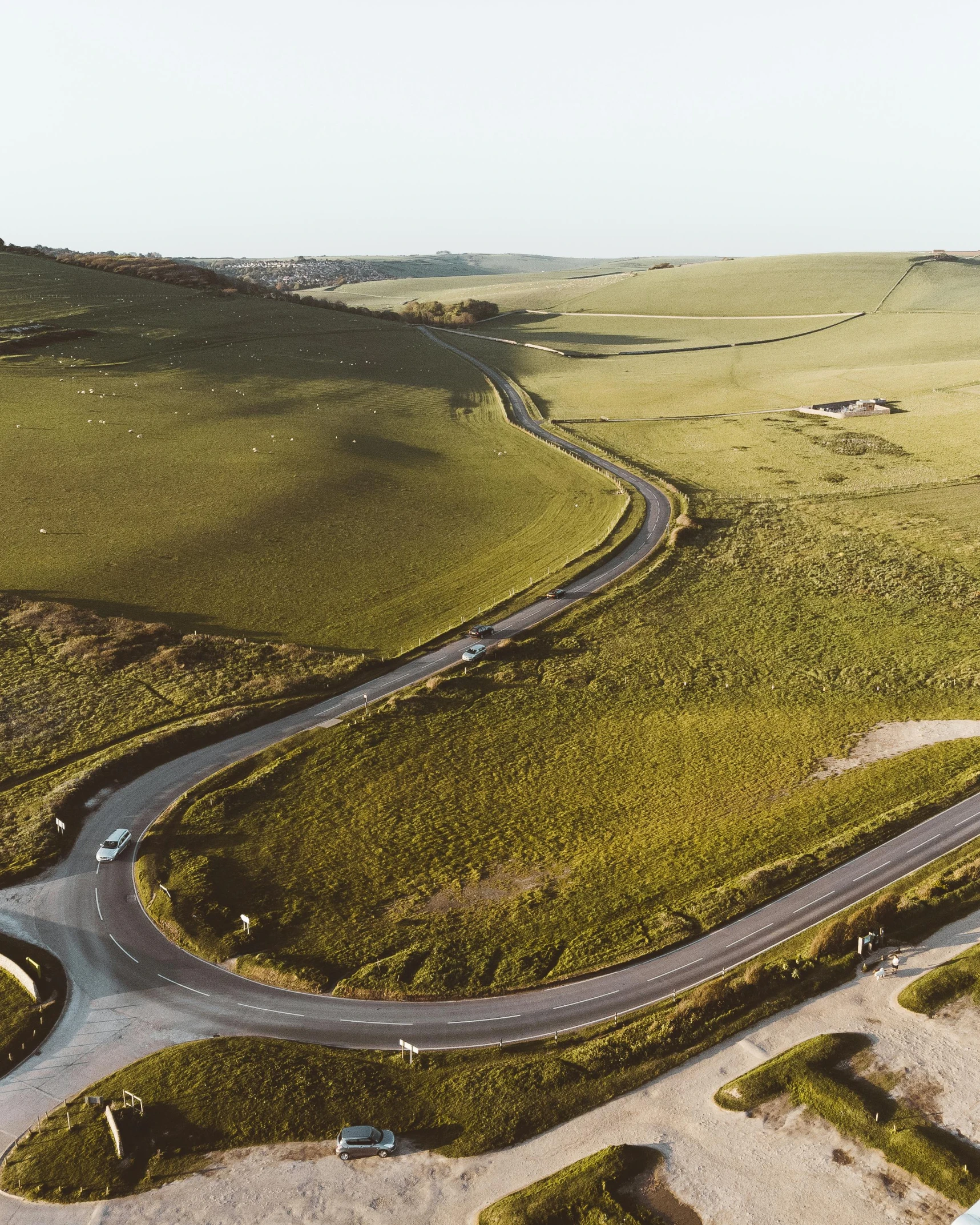 an aerial view of a winding country road, unsplash contest winner, an expansive grassy plain, hills, cliffs of dover, farming