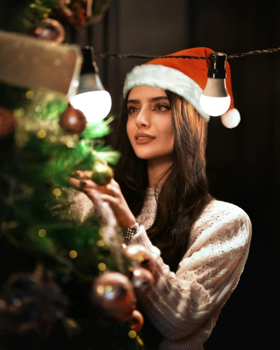 a woman in a santa hat decorating a christmas tree, trending on pexels, mood light, dua lipa, non binary model, square