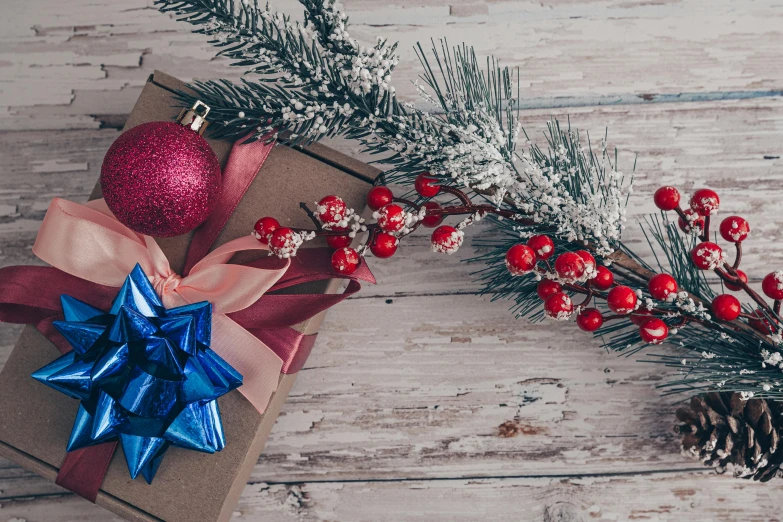 a christmas gift sitting on top of a wooden table, by Alexander Brook, pexels contest winner, hurufiyya, maroon and blue accents, red and white color theme, background image, branches wrapped